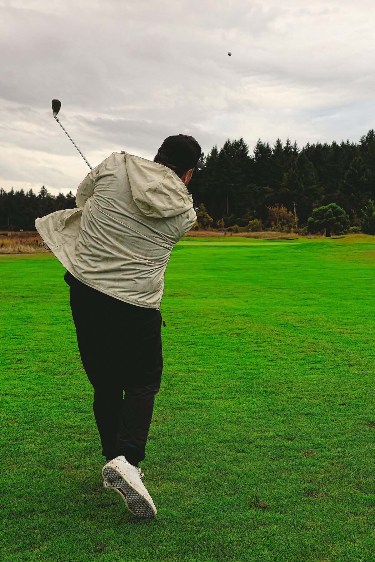 Golfer at the top of a follow through, ball away down the fairway