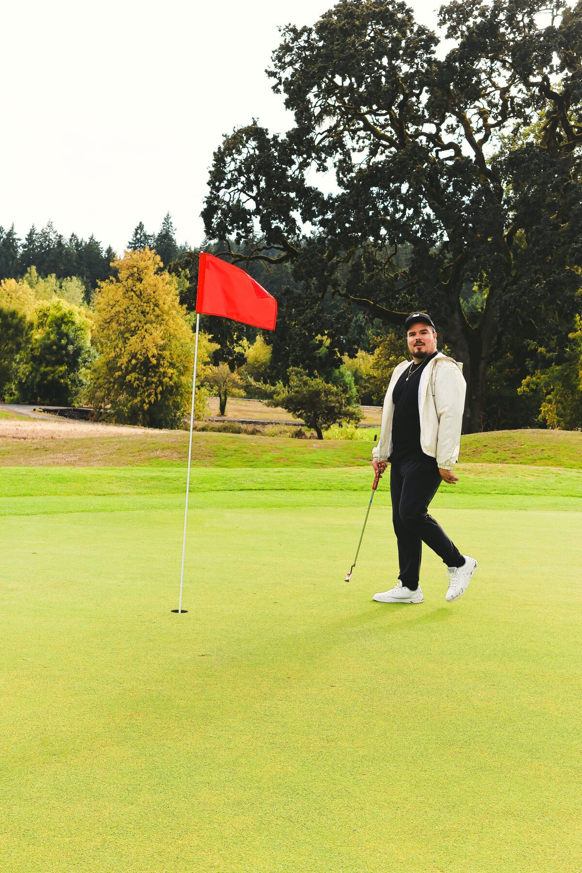 A red pin on the green, golfer walking in from the fringe