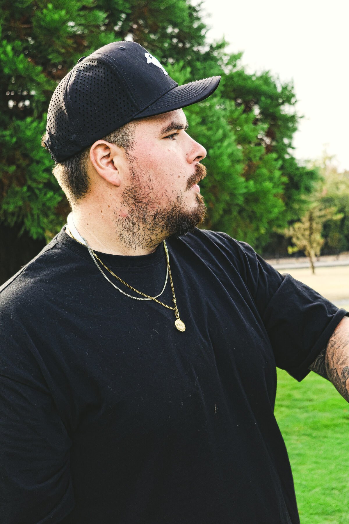 Portrait of a golfer in a black cap between shots, treeline behind