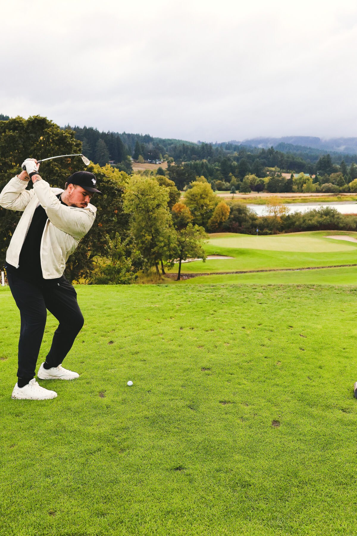 Mid swing on an open fairway, water in the distance