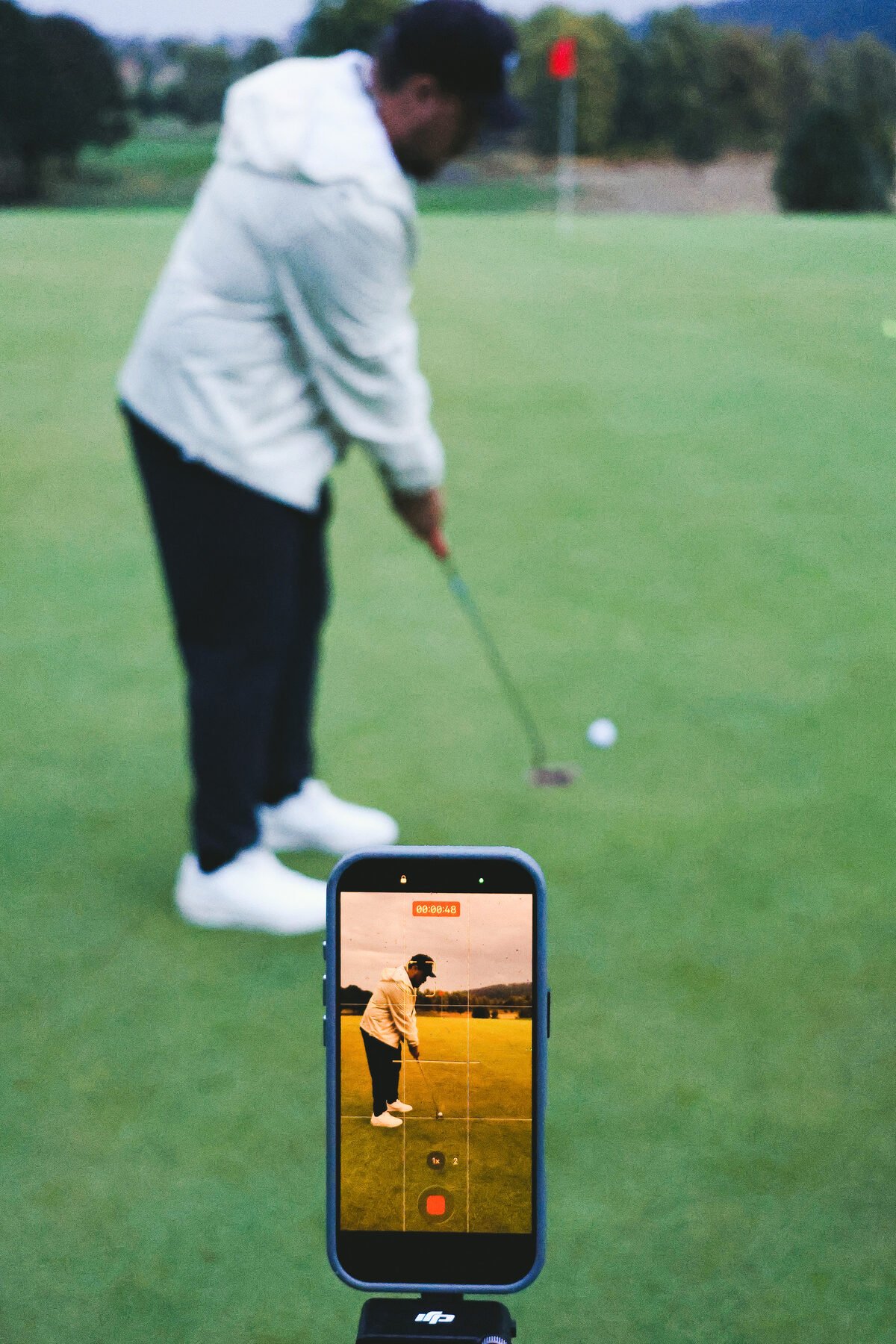 Filming a putt on a phone rig, the green beyond
