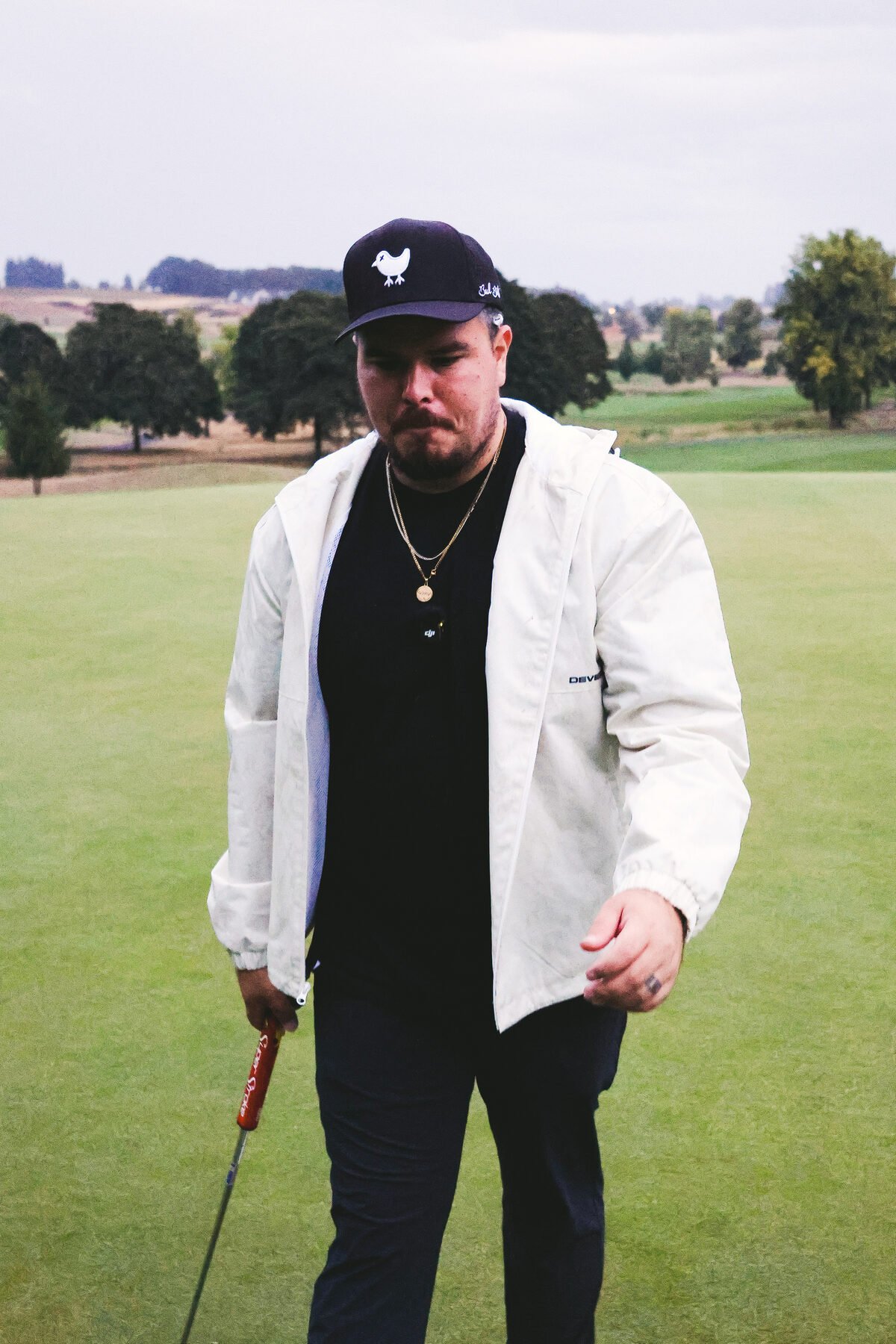 Full length portrait of a golfer on the green, club at his side