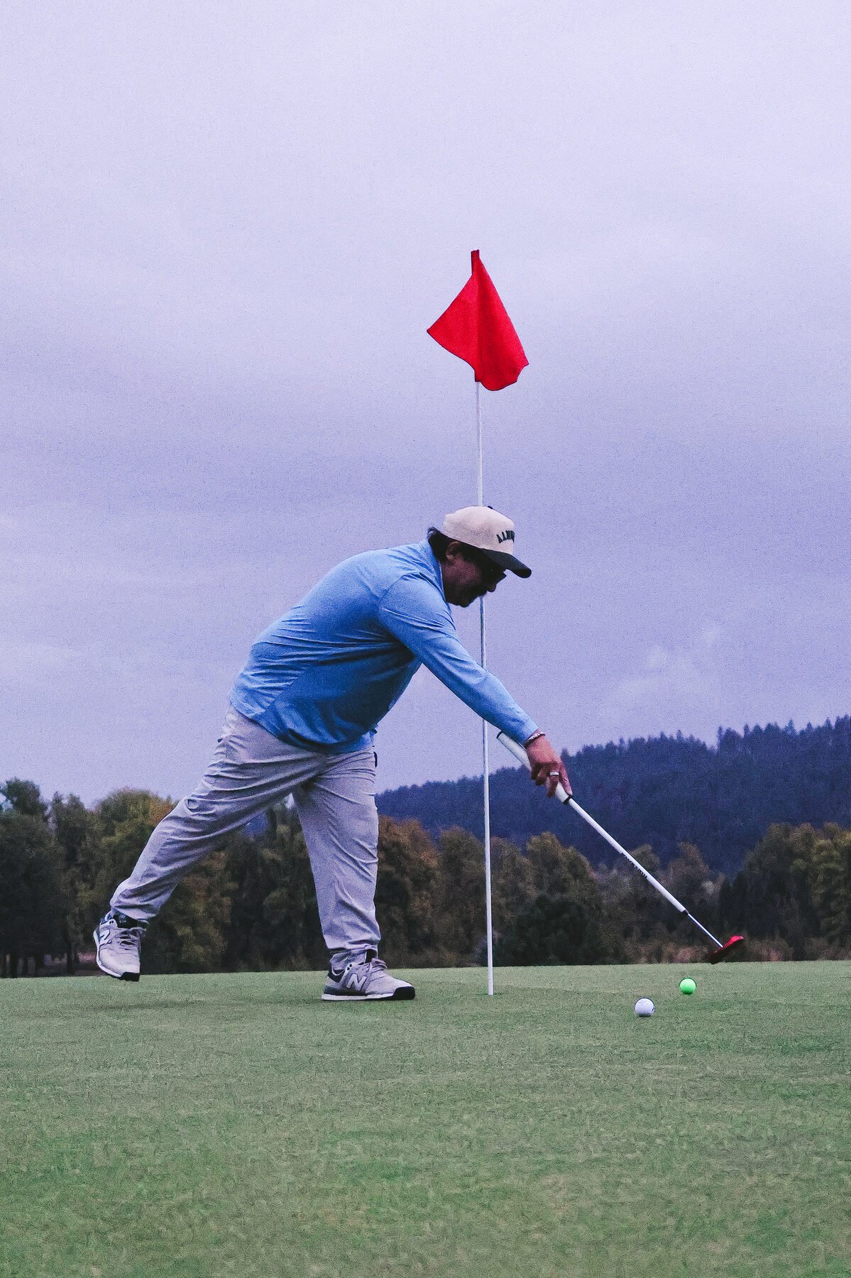 Golfer putting out beside the pin under a grey sky